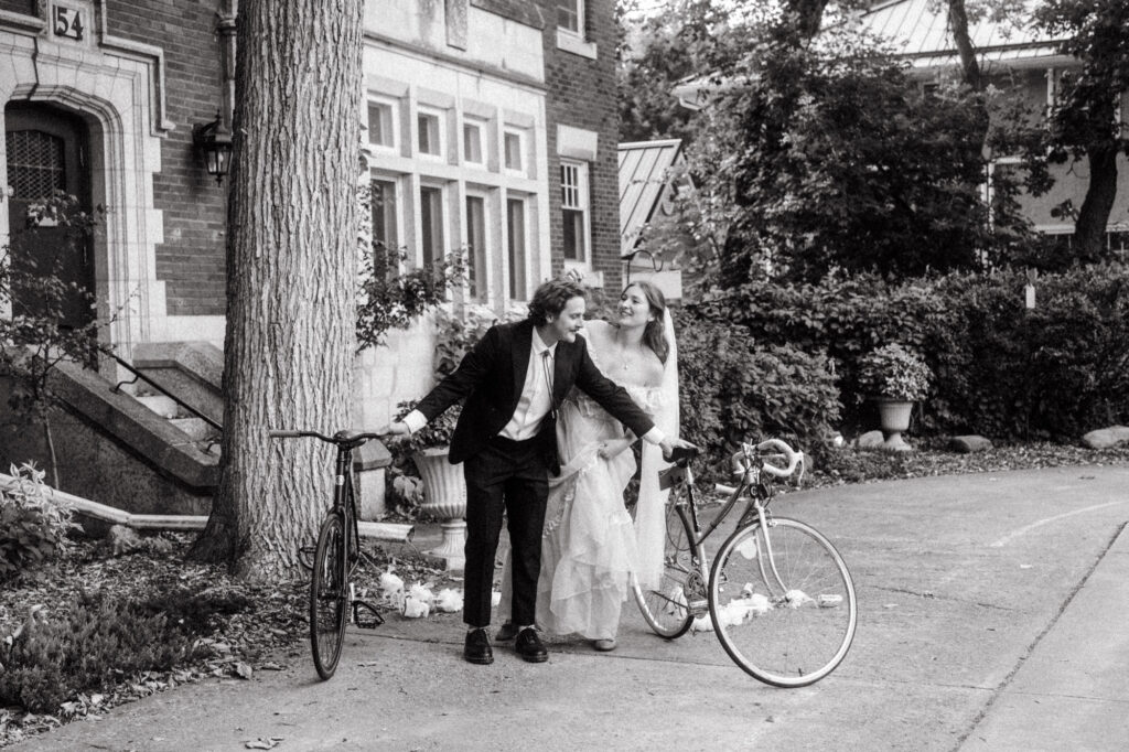 documentary-style wedding photo of bride and groom biking away on wedding day