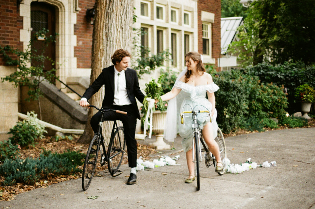 documentary-style wedding photo of bride and groom biking away on wedding day