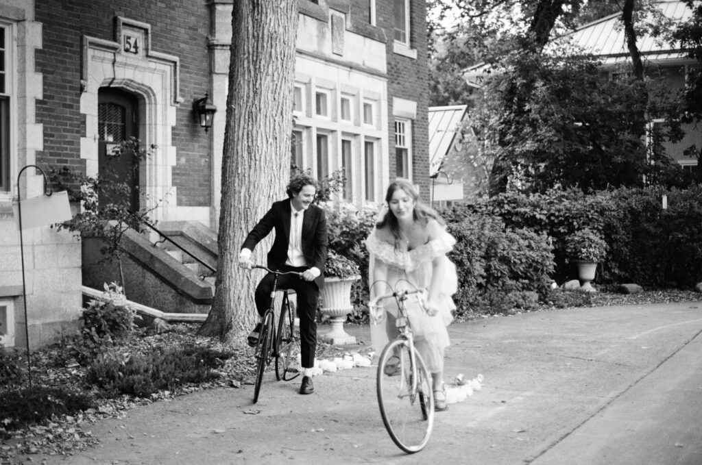 documentary-style wedding photo of bride and groom biking away on wedding day