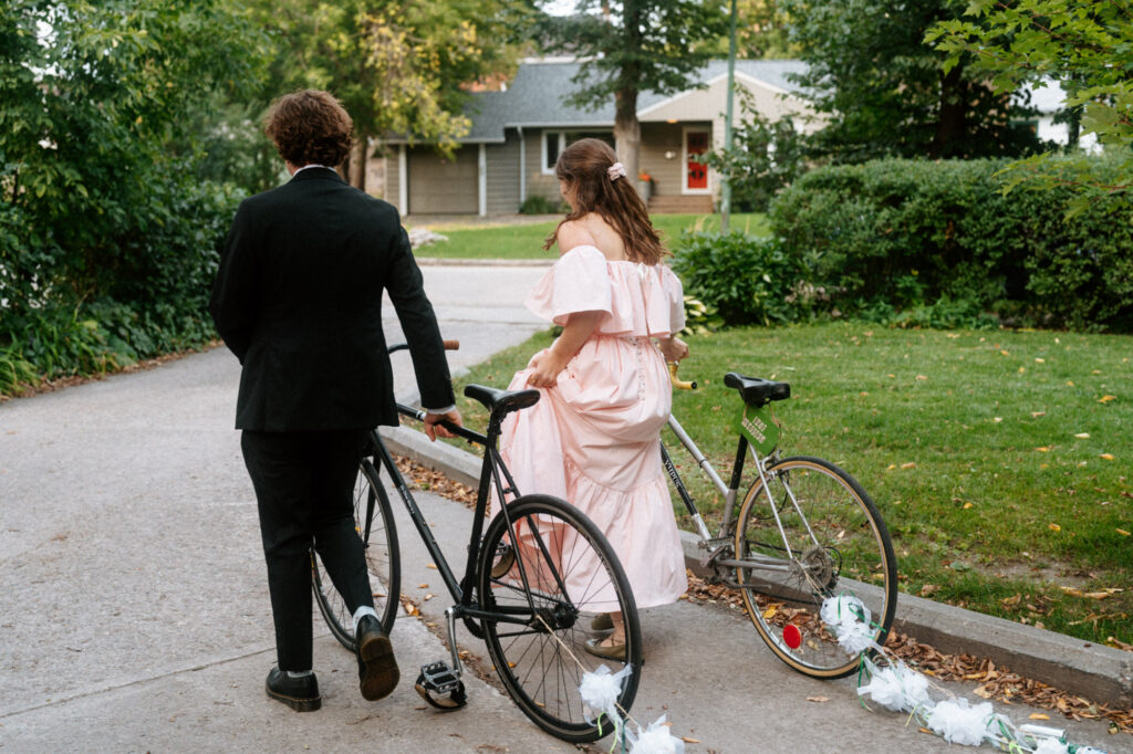 documentary-style wedding photo of bride and groom biking away on wedding day